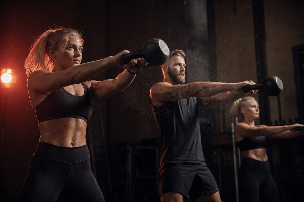 Tre utøvere som trener kettlebell-sving i takt