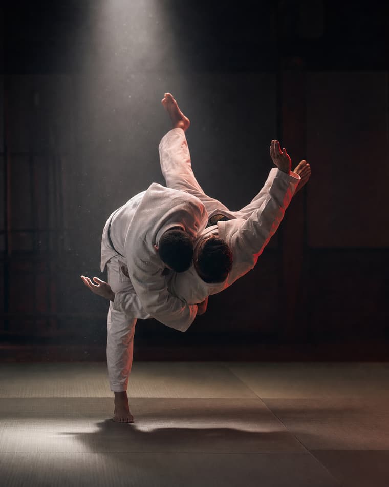 To jujutsu-utøvere i hvite drakter demonstrerer et hoftekast på tatami