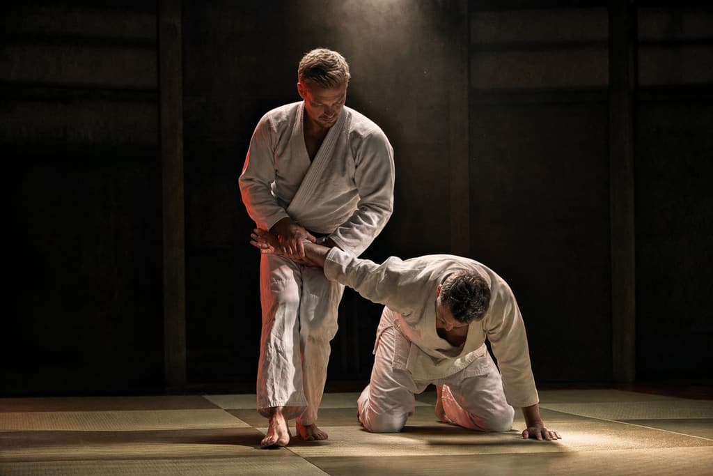 Jujutsu-utøver som kontrollerer treningspartneren med en håndleddslås på tatami